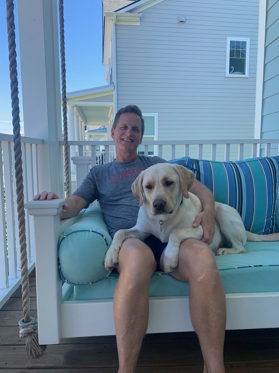 Jimmy on a porch swing with a yellow Lab